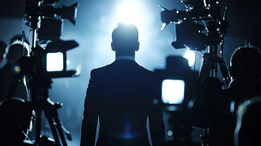 Silhouetted executive surrounded by cameras during group media training, preparing for high-stakes public appearances.